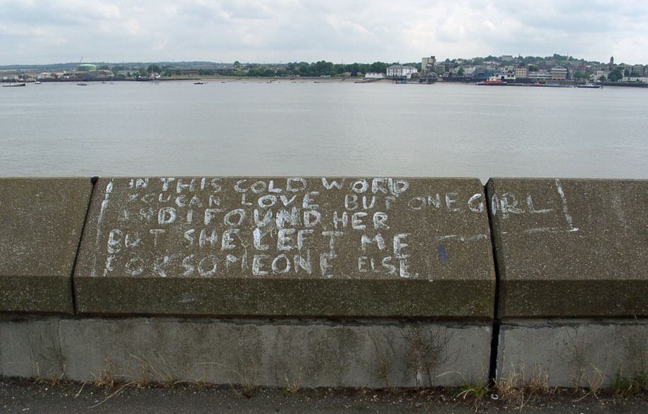 Grafitti on the sea wall at Tilbury with Gravesend on the other side of the Thames.